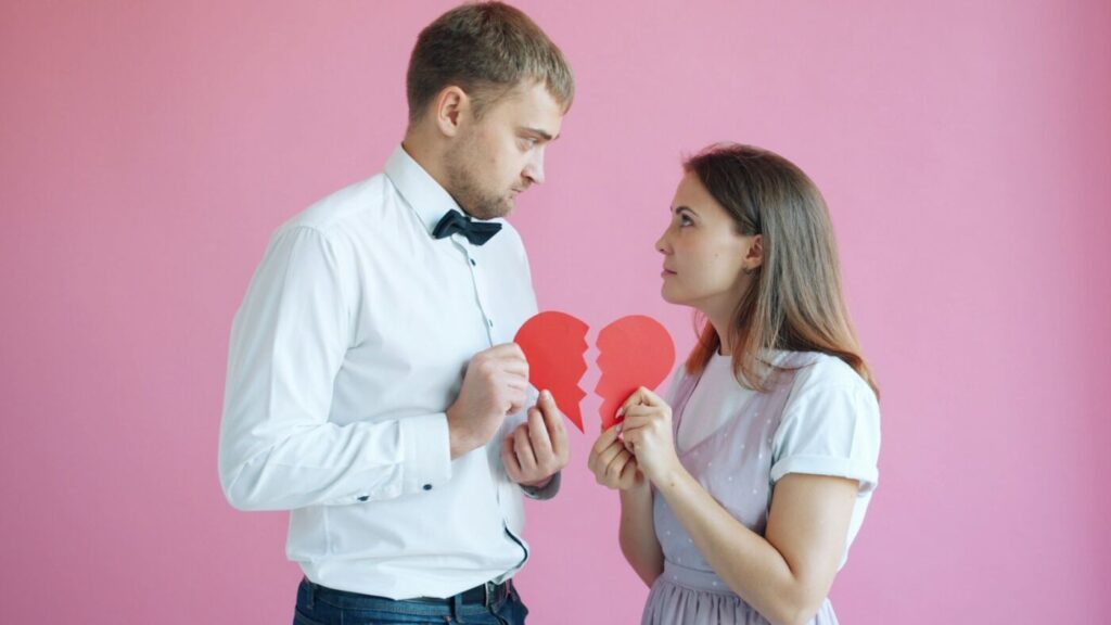 Pareja sujetando las dos mitades de un corazón de papel roto
